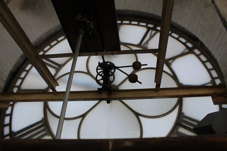 A close-up of mechanical clock hands against a pearlescent clock face 