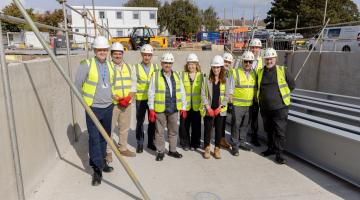 A group of people in his vis jackets stood in the structure of a pool on a building site