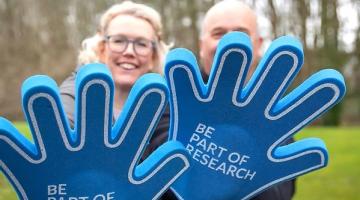Two foam gloves with the words Be Part Of Research written across