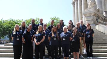 Wellbeing Service team members in branded tops stand on the steps of the Guildhall for a team photo
