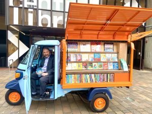 Portsmouth City Council leader Steve Pitt sitting in the front seat of the new blue and orange tuk tuk which will deliver library books