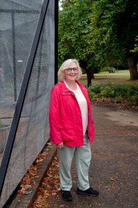 Debra Hamilton in a red jacket in front of the birdcage at Victoria Park