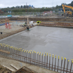 concrete being levelled with a float. Two workmen sitting