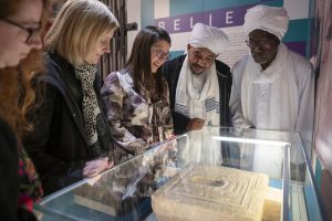 Ancient Sudan exhibition, group of adults looking at an ancient carving table