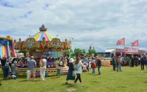 Groups of people walking around a funfair at Portsmouth Armed Forces Day 2024