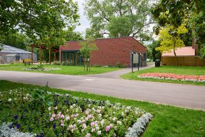 The Green House building in Victoria Park with a flowerbed in the forefront of the image