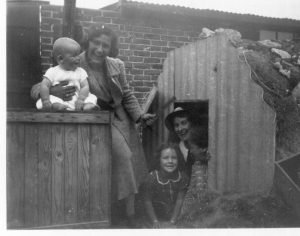 Joan Wright (lower centre) and her family by the entrance to their air raid shelter, after an air raid, 1940. She lived in Baffins.