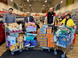 The leader of Portsmouth City Council with three others standing behind shopping trollies filled with animal food and supplies inside Jollyes pet shop.