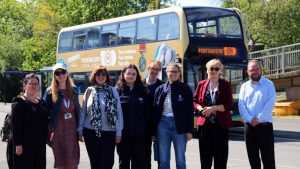 Portsmouth Museums staff in front of a bus promoting the Portsmouth100 Your museum. Your stories. Your city exhibition launching in October