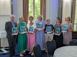 A group of teachers holding the Bright Sparks book and smiling